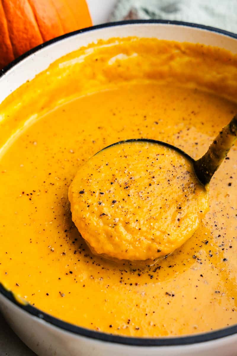 Close-up view of a ladle serving homemade pumpkin soup.