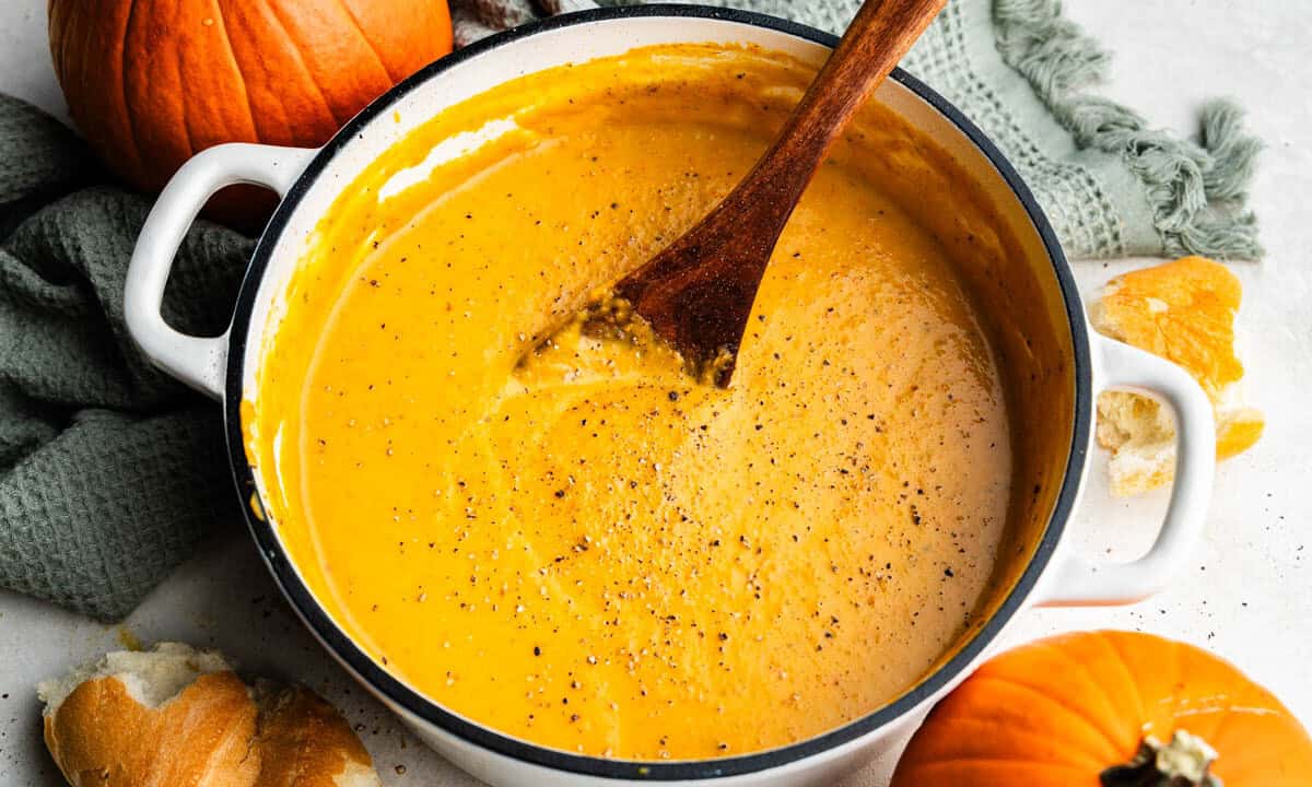 A pot of homemade pumpkin soup with a spoon resting in the middle.