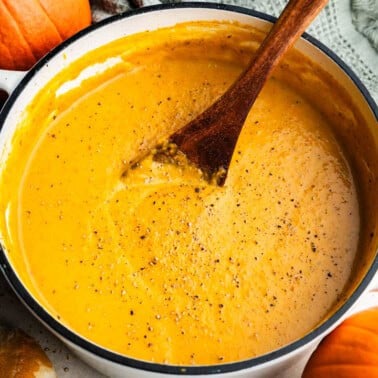 A pot of homemade pumpkin soup with a spoon resting in the middle.