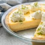 A whole key lime pie with a piece removed.