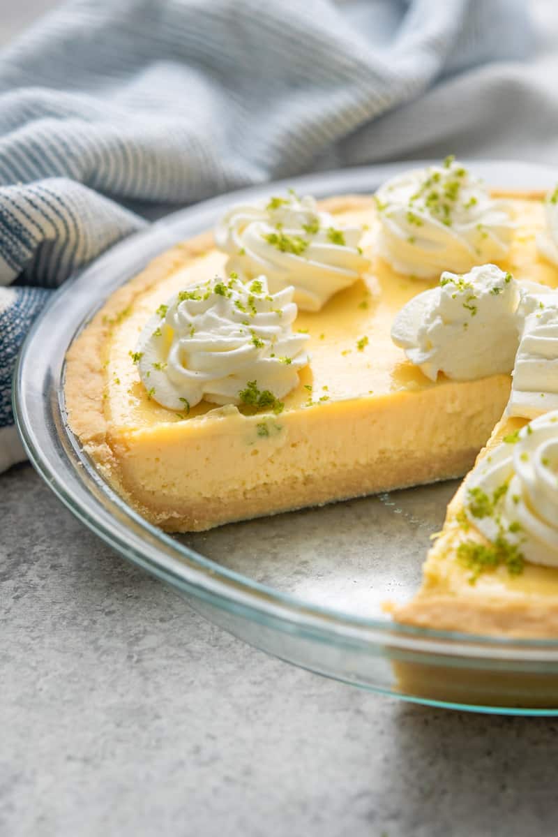 A whole key lime pie with a piece removed.