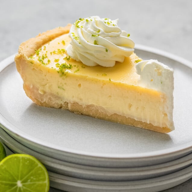 A slice of key lime pie on a stack of plates.