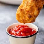 Dunking a chicken tender into ketchup.