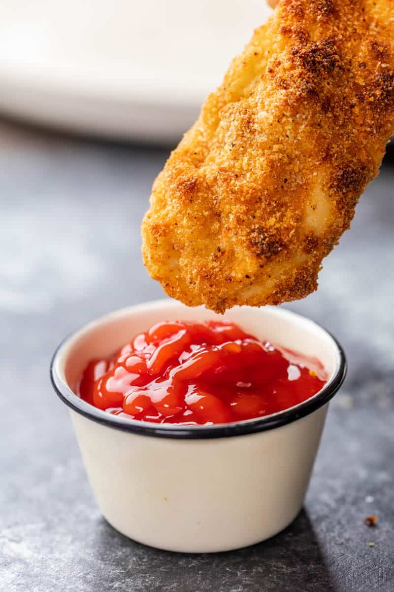 Dunking a chicken tender into ketchup.