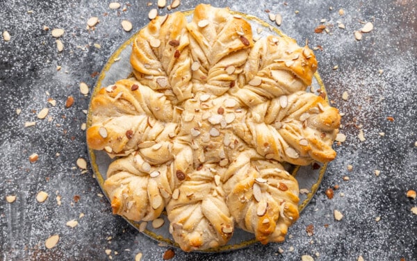 Overhead view of a loaf of Almond Star Bread surrounded by loosely scattered slivered almonds.