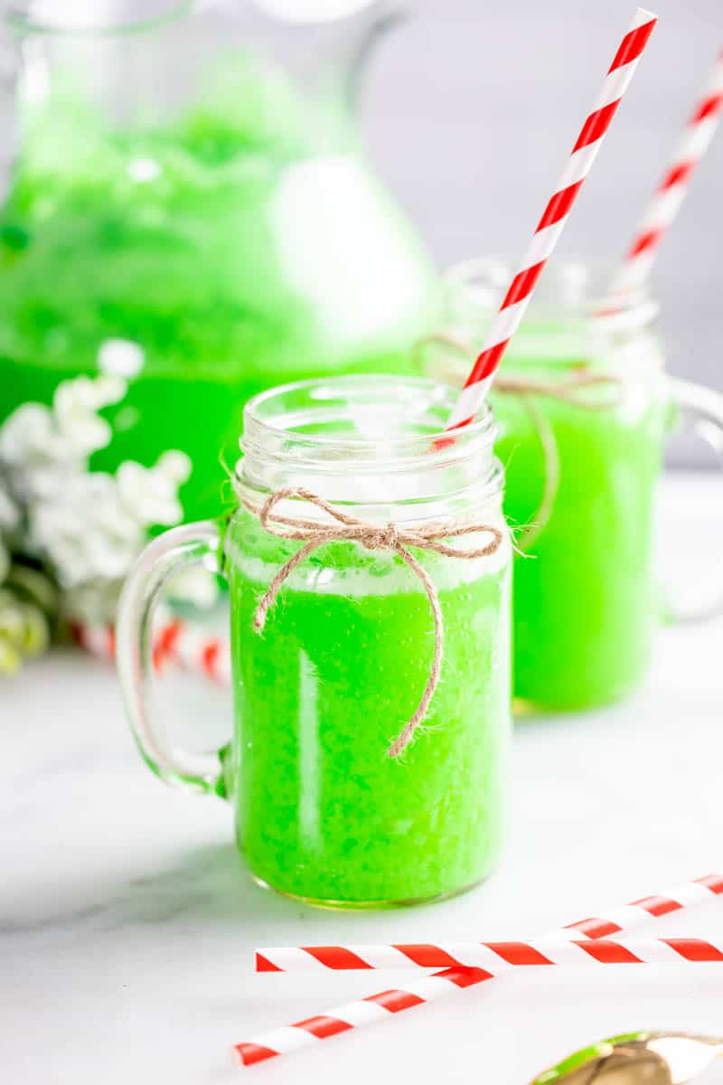 Grinch punch in glasses with a red and white straw.