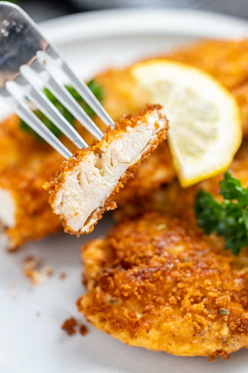 A piece of a chicken cutlet stuck on a fork.