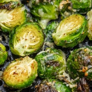 Close up view of brussel sprouts in an air fryer basket.