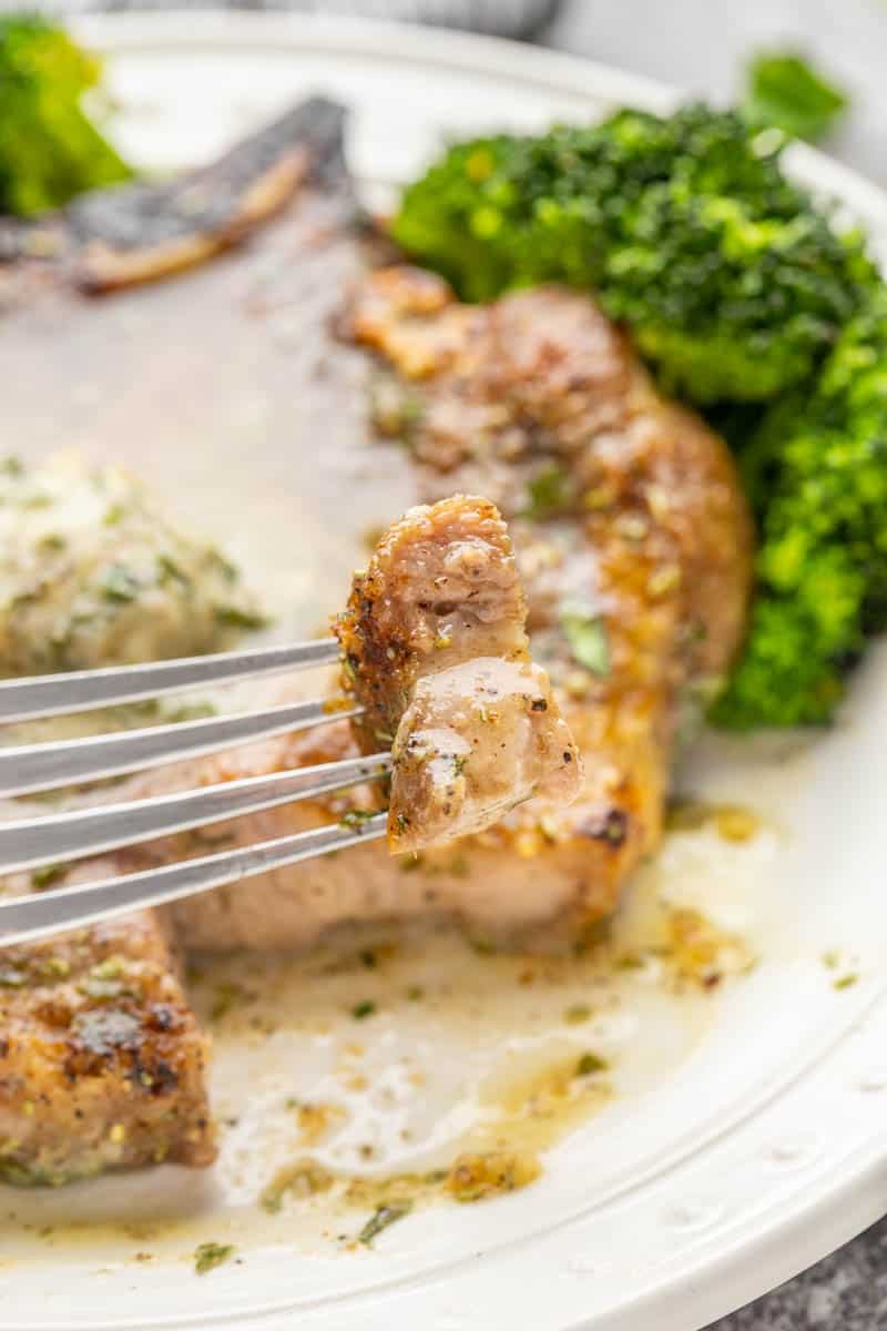 A bite sized piece of pork chop on a fork.