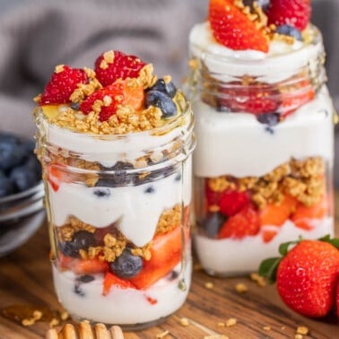 2 glass jars filled with yogurt and berries parfait.