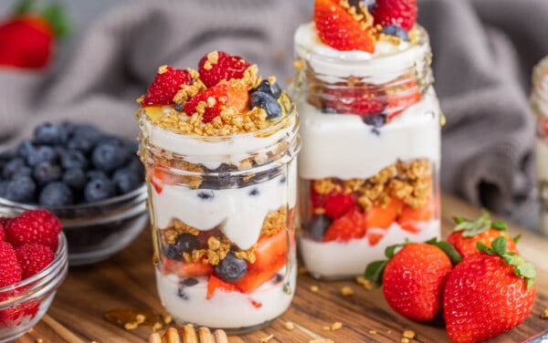 2 glass jars filled with yogurt and berries parfait.