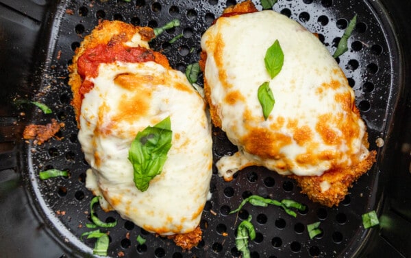 Overhead view looking into an air fryer basket with chicken parmesan.