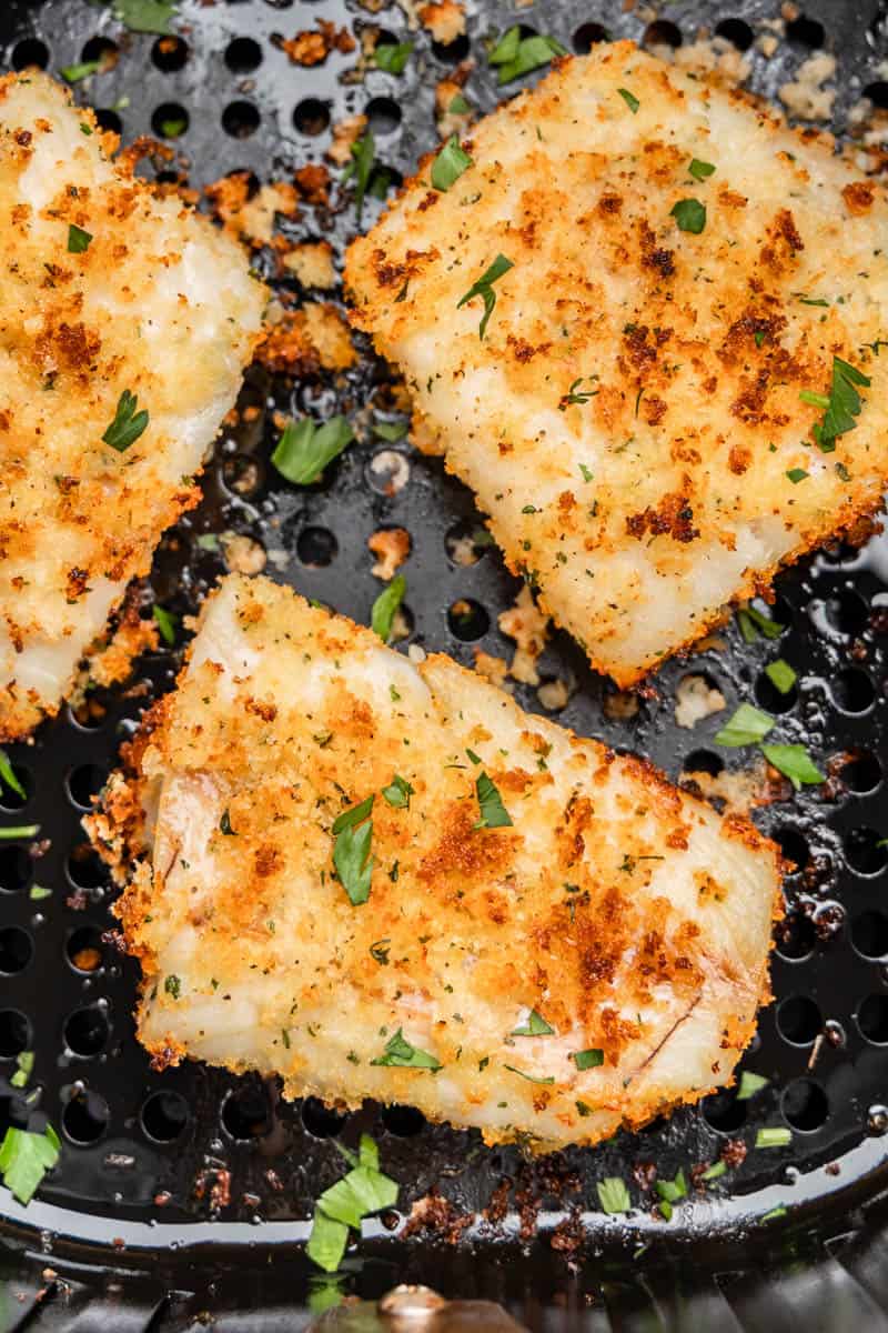 Overhead view of crispy fish in an air fryer basket.