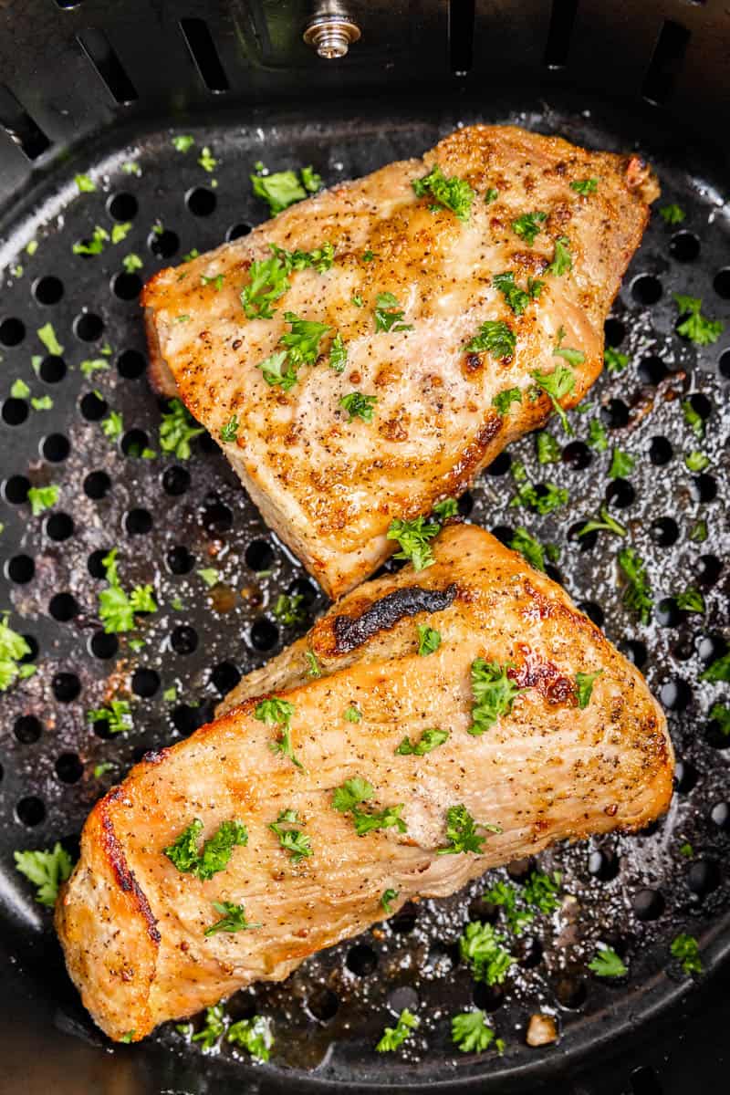 Overhead view looking into an air fryer basket with pork tenderloin.