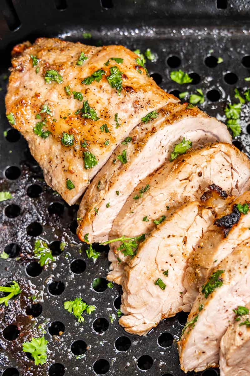 A sliced pork tenderloin in an air fryer basket.