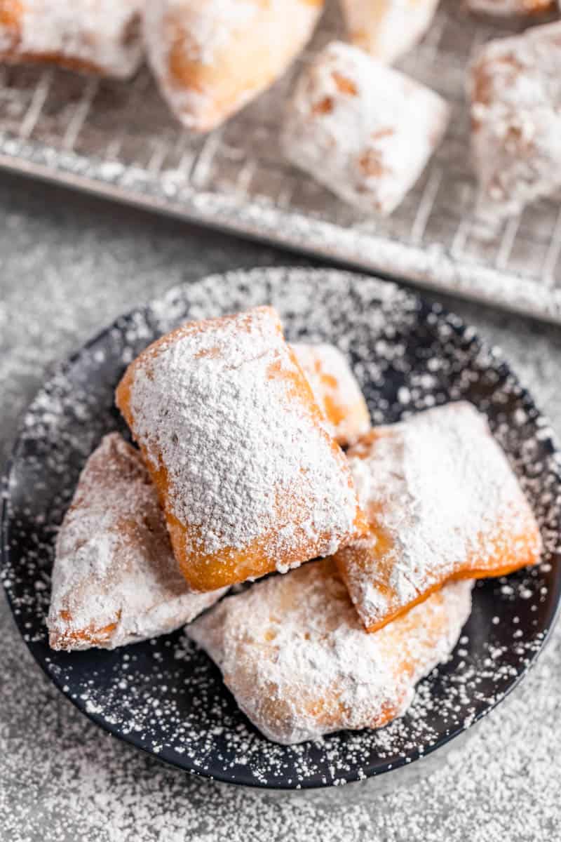 Overhead view of a stack of beignets on a dessert plate.