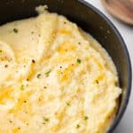 Overhead view of cheese grits in a cast iron pan.