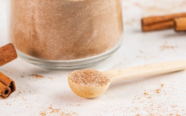 Close up view of a wooden spoon filled with homemade cinnamon sugar.