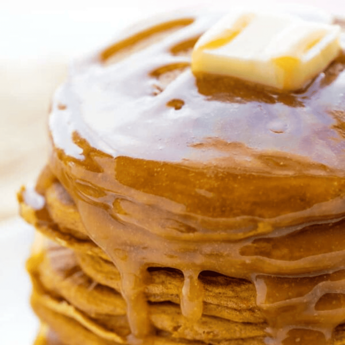 stack of pumpkin pancakes smothered with syrup.