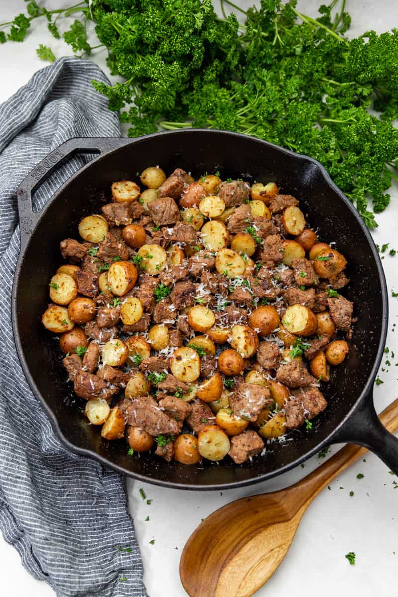 Top view of a cast iron skillet filled with steak and potatoes.