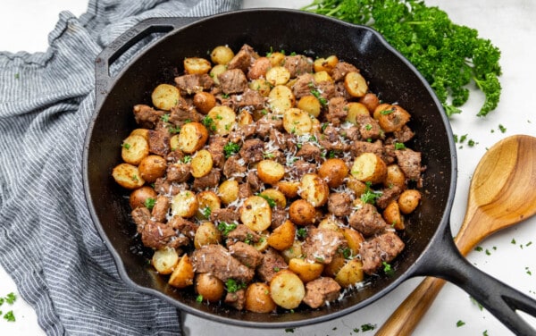 Looking into a cast iron pan with steak bites and potatoes.
