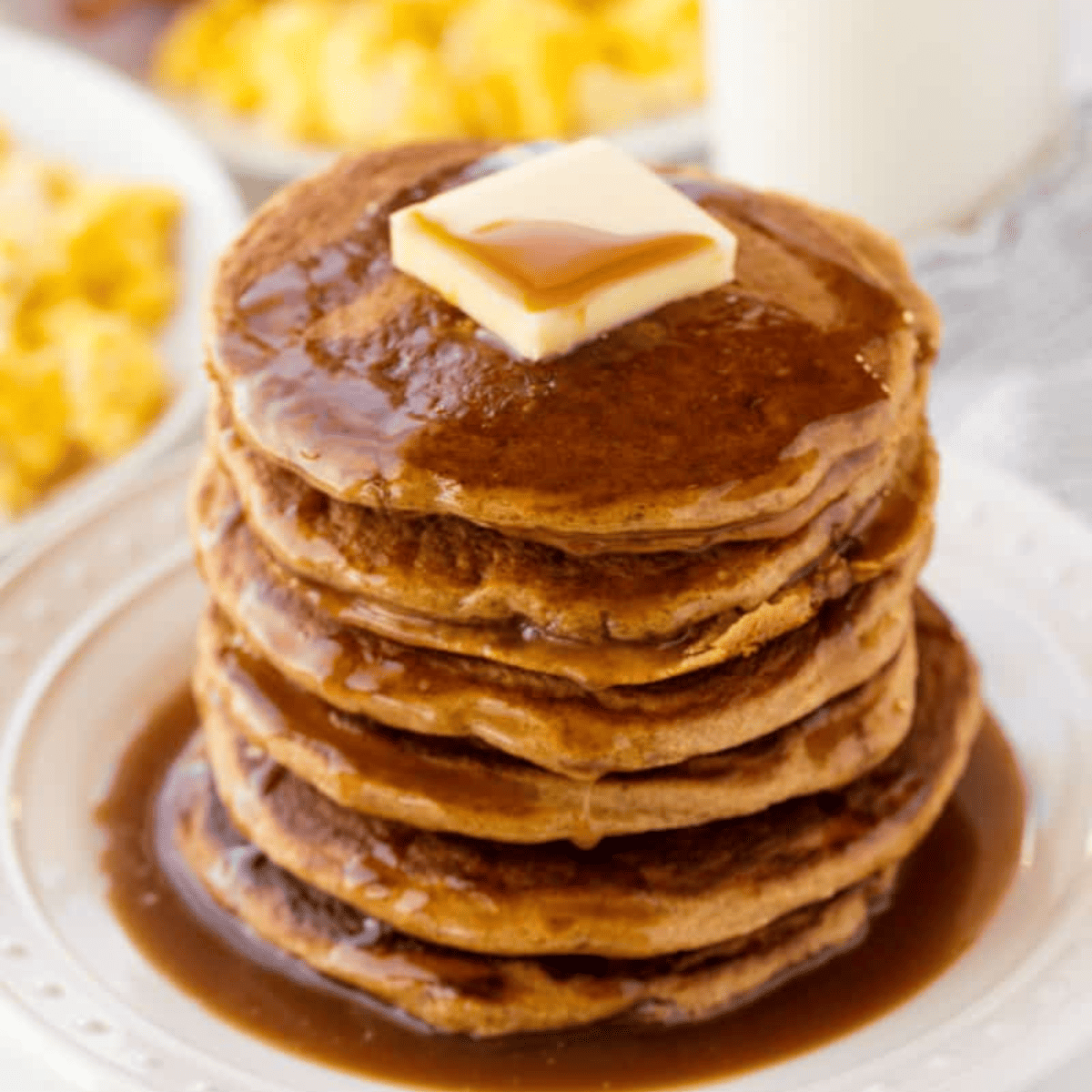 Stack of healthy whole wheat pancakes topped with pure maple syrup.