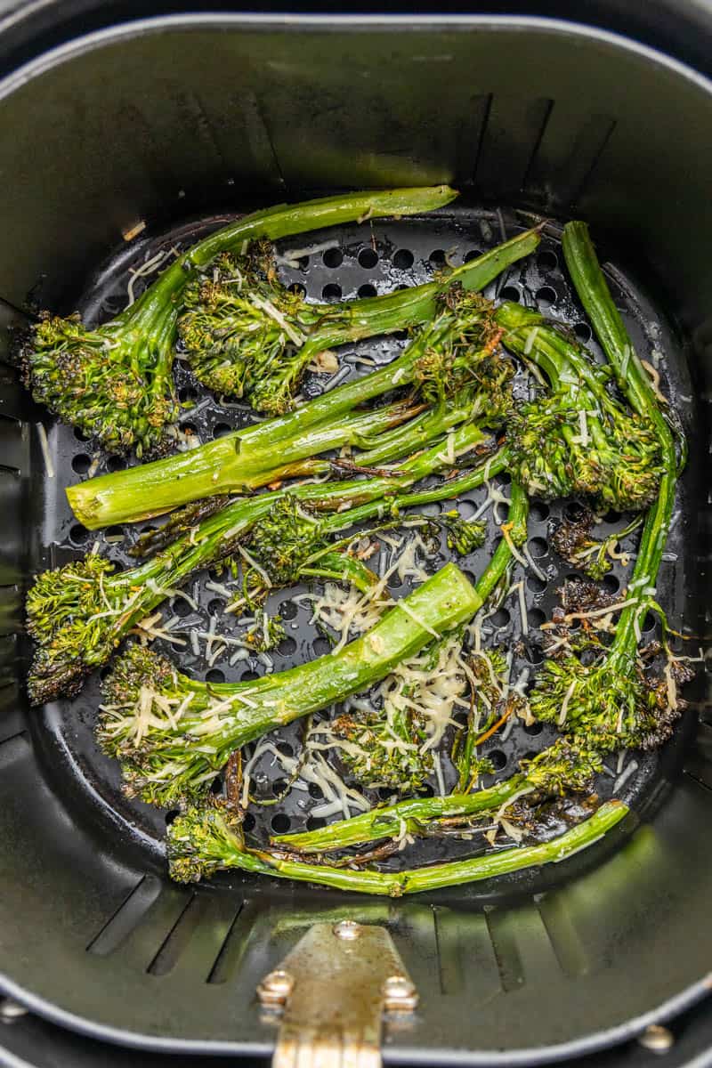 Broccolini in an air fryer basket.
