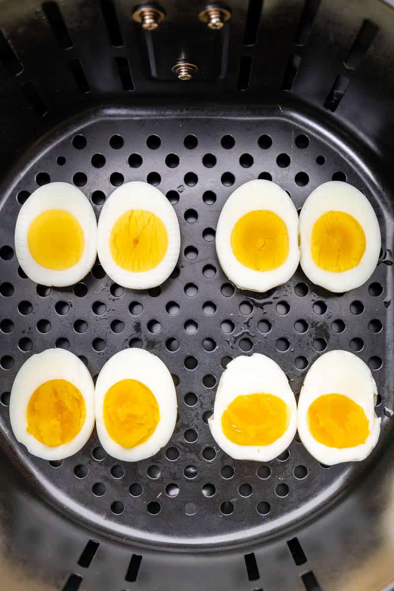 Overhead view looking into a deep fryer basket with hard-boiled egg halves.