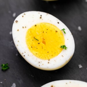 Close up view of a hard boiled egg cut in half and sprinkled with parsley.