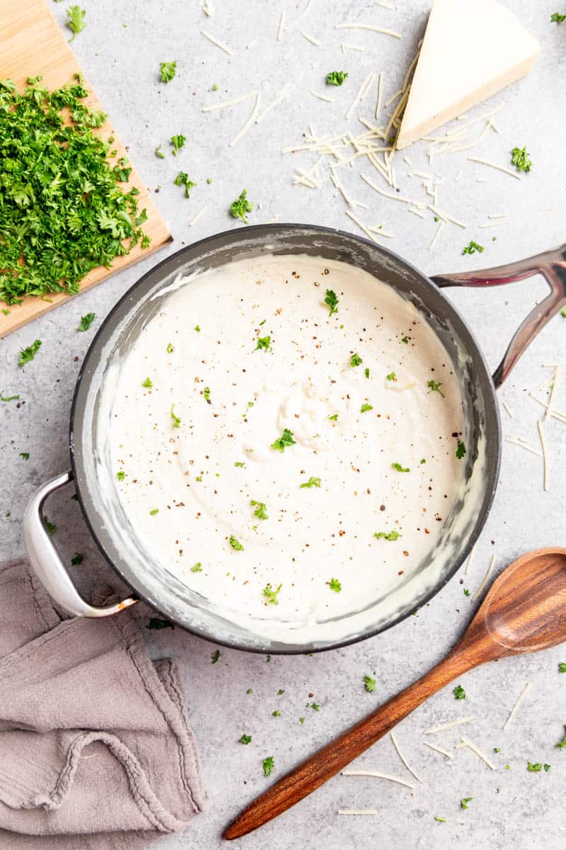 Overhead view of homemade Alfredo sauce in a stainless steel pot.