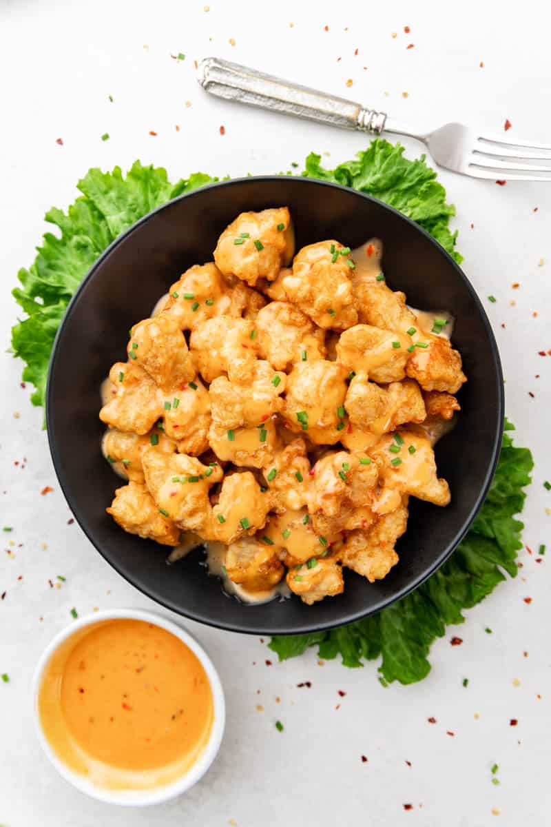 Overhead view of a black bowl filled with bang bang chicken.