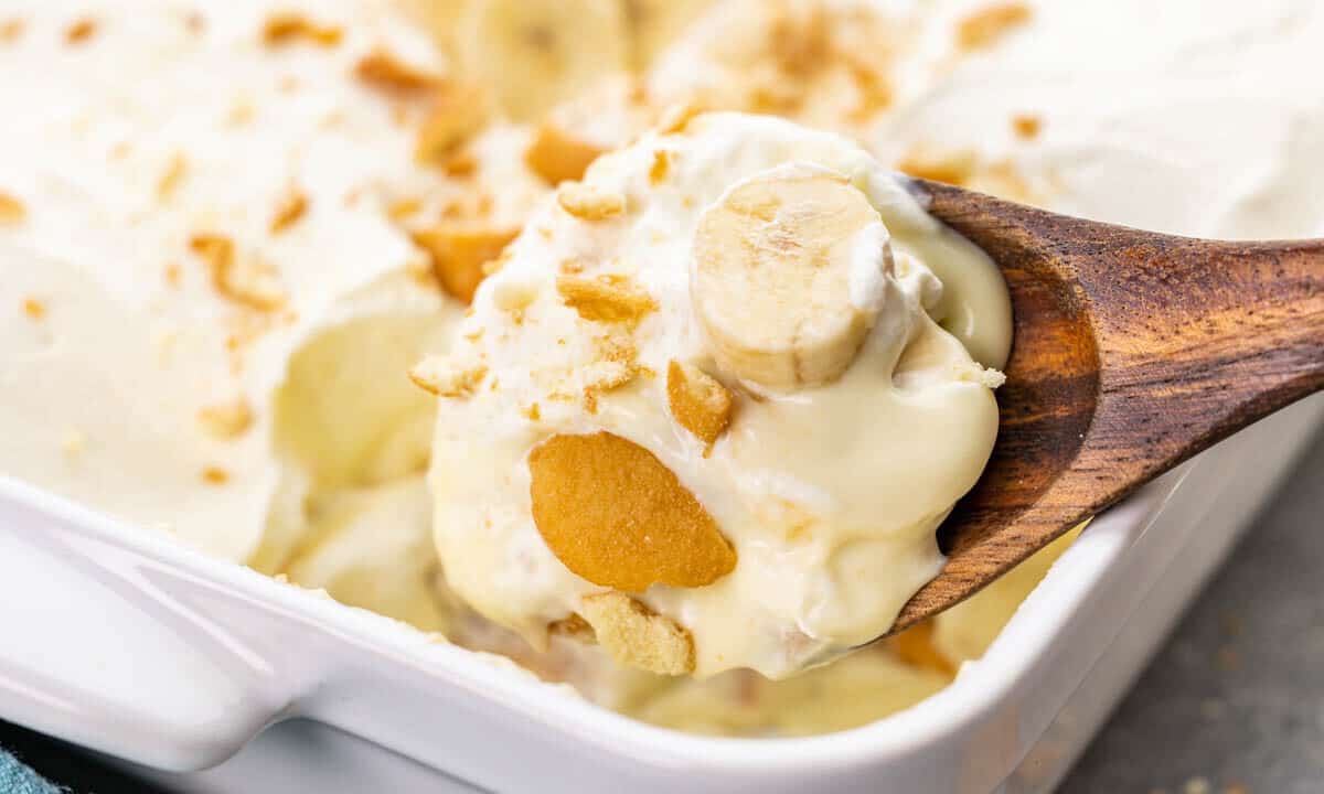 A wooden spoon holding a lot of banana pudding.