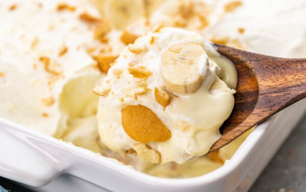 A wooden spoon holding a lot of banana pudding.