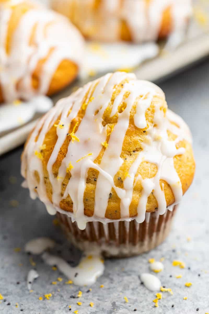 Close-up view of lemon poppy seed muffin with a drizzle of icing on top.