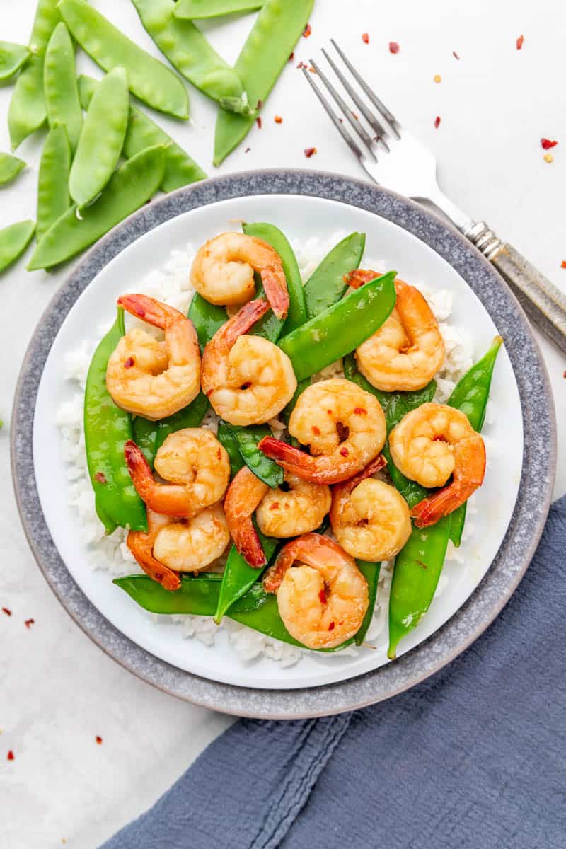 Overhead view of a plate full of honey garlic shrimp and snow peas.