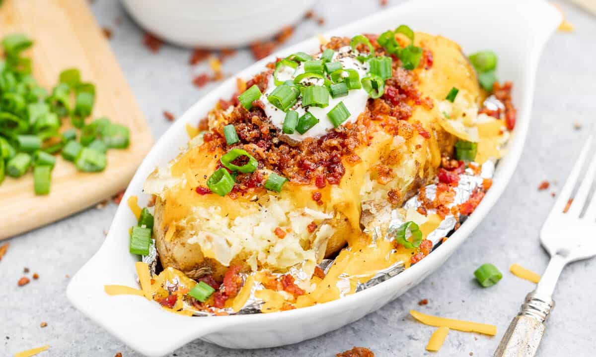 A loaded baked potato in a ceramic dish.
