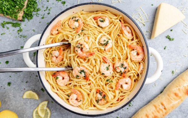 Overhead view of shrimp linguine in a white pot with tongs resting in.