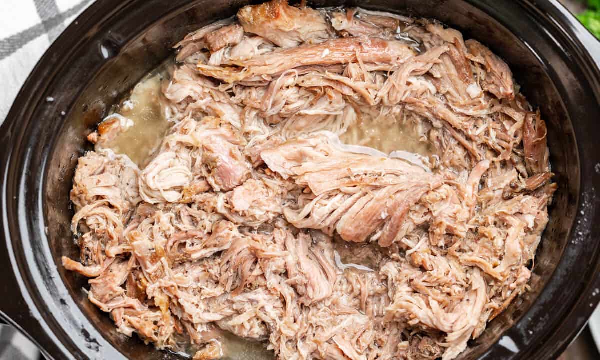Overhead view of pulled pork in a slow cooker.