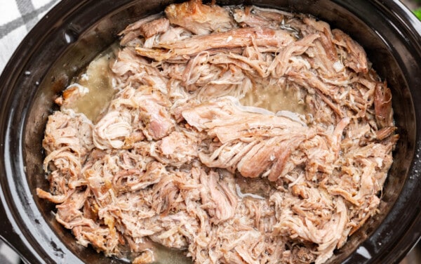 Overhead view of pulled pork in a slow cooker.