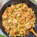Overhead view of shrimp fried rice in a wok with a wooden spoon.