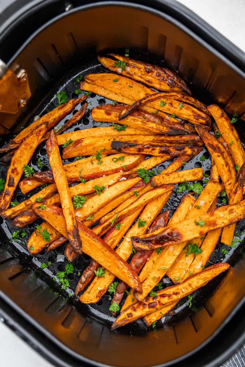 Top view of an air fryer basket filled with sweet potato fries.