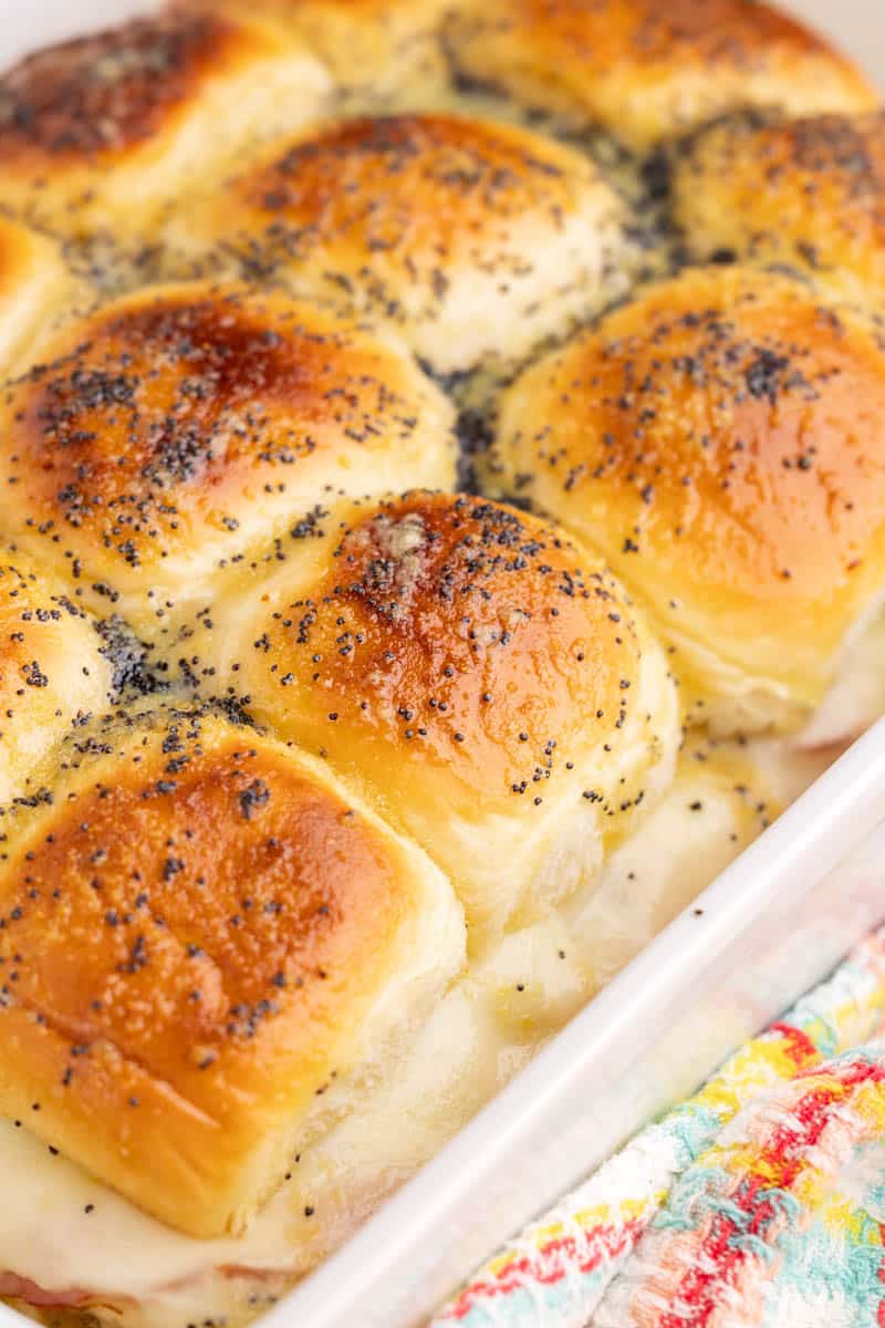 A gratin dish filled with plenty of ham and cheese sliders.