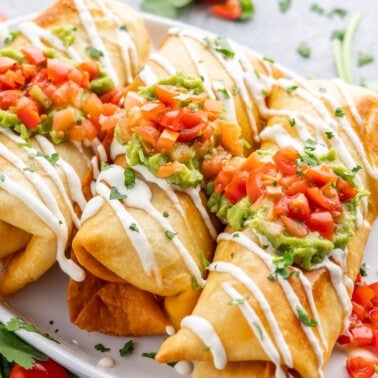 Overhead view of three chimichangas on a white serving platter.