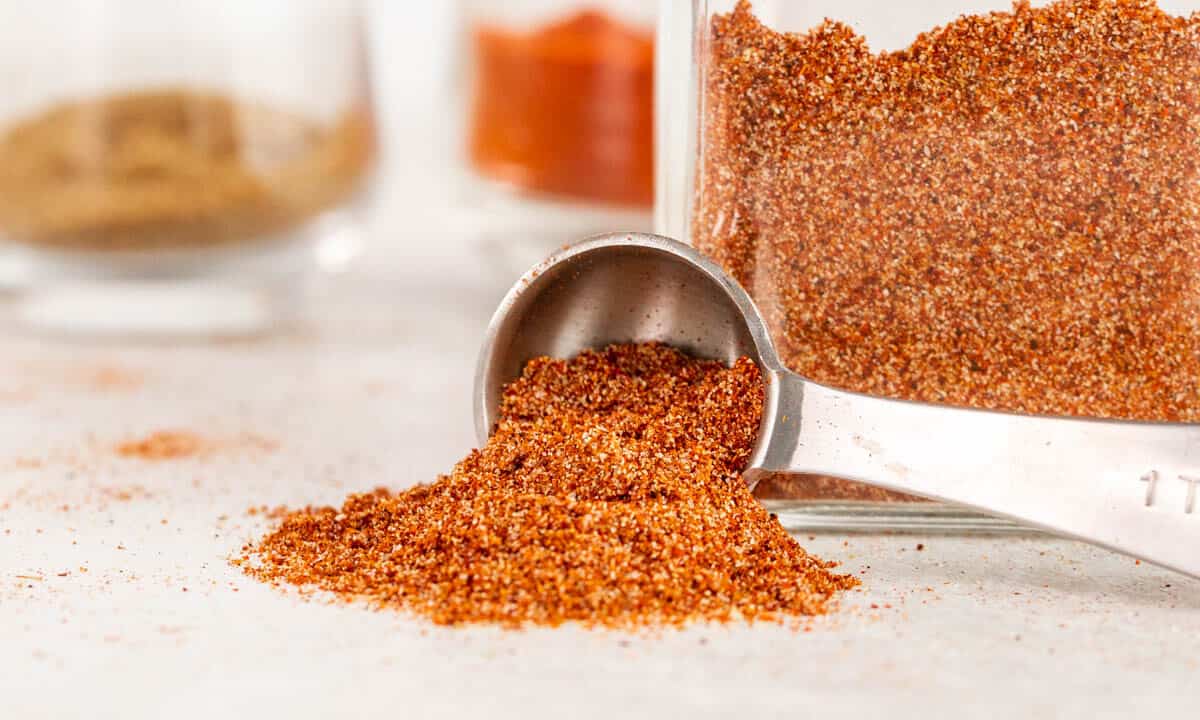 A teaspoon on its side with homemade taco seasoning spilling out.