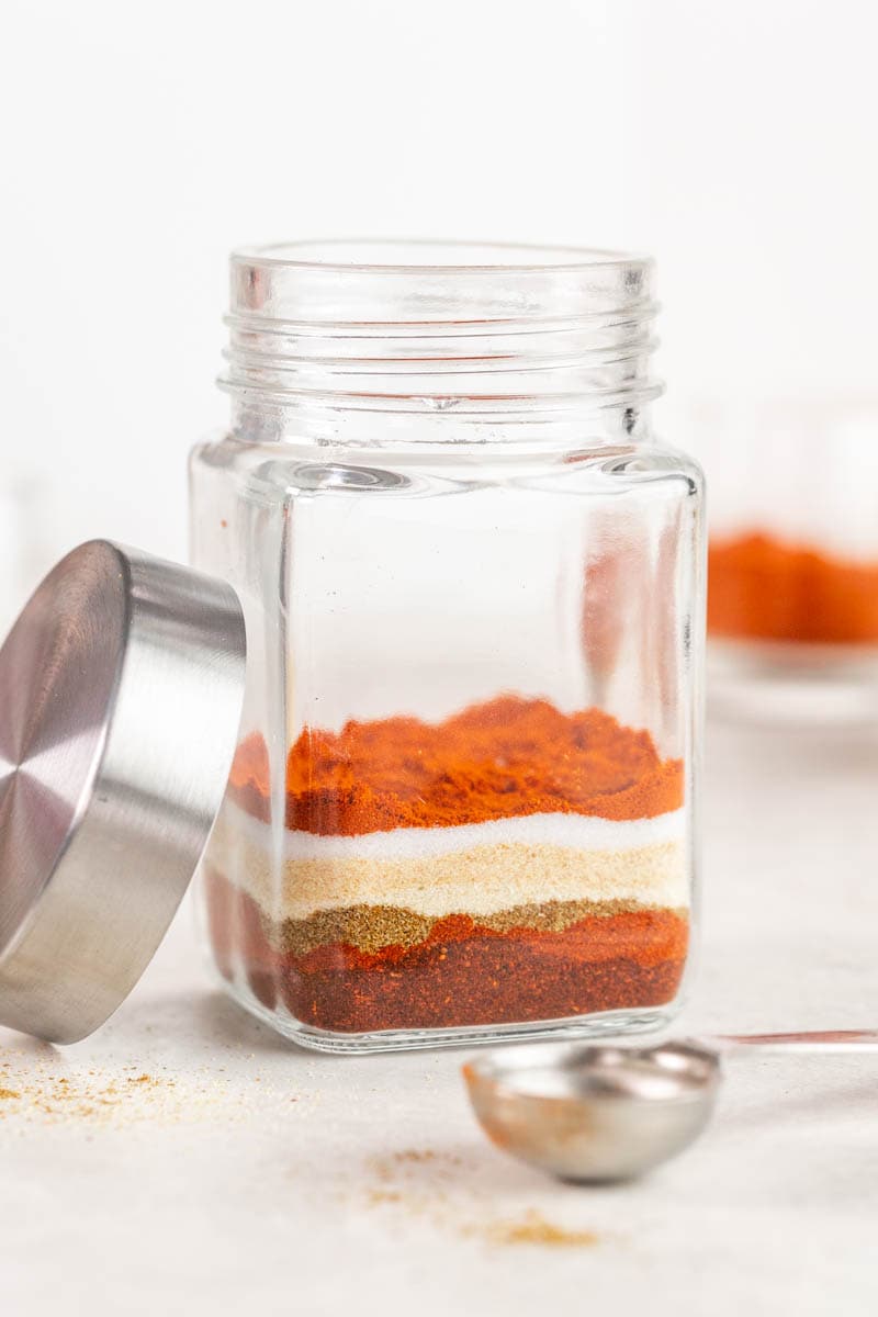 A glass jar half filled with homemade taco seasonings.