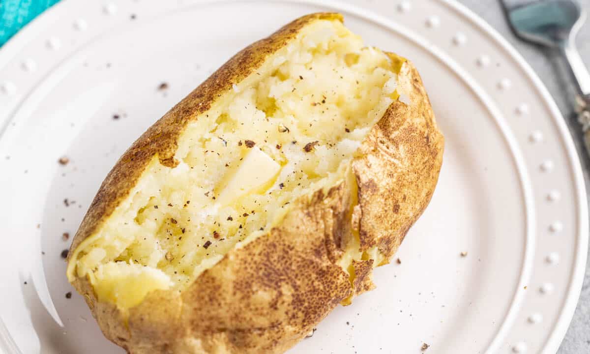 Overhead view of a baked potato split open with butter inside.