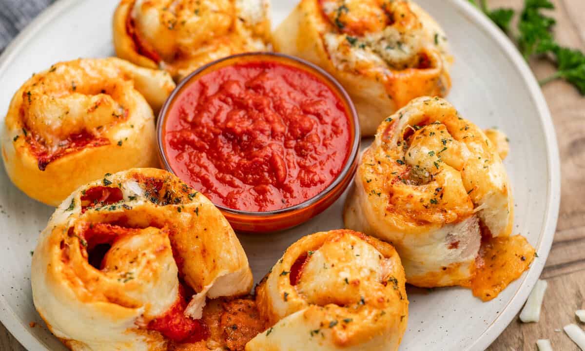 Close up view of pizza rolls and marinara sauce of dipping on a serving platter.