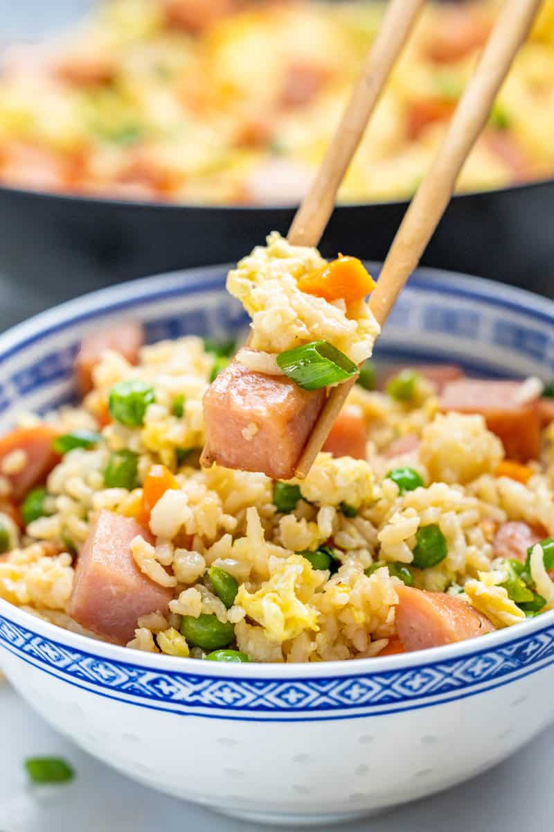 Chopsticks holding a small amount of spam fried rice.