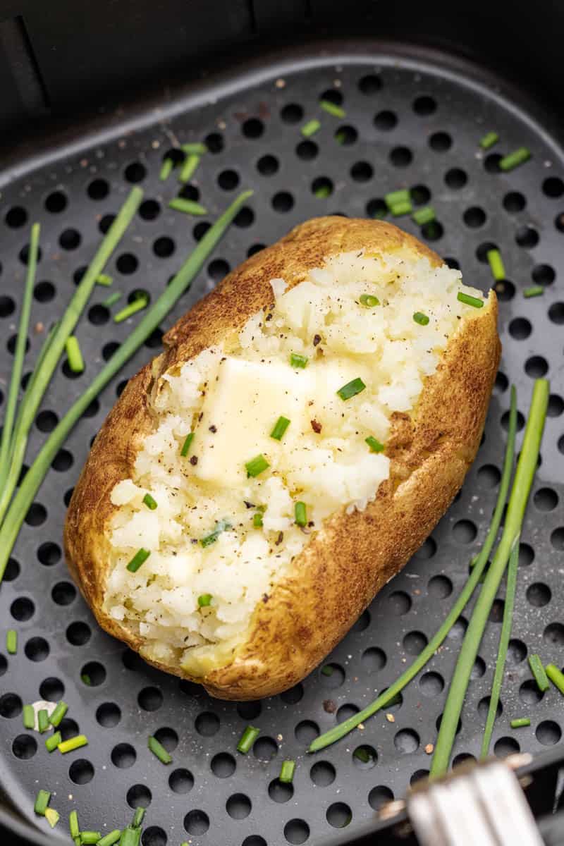 Overhead view of a baked potato in an air fryer basket.