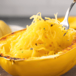 A fork scooping up baked spaghetti squash from a freshly baked squash half.